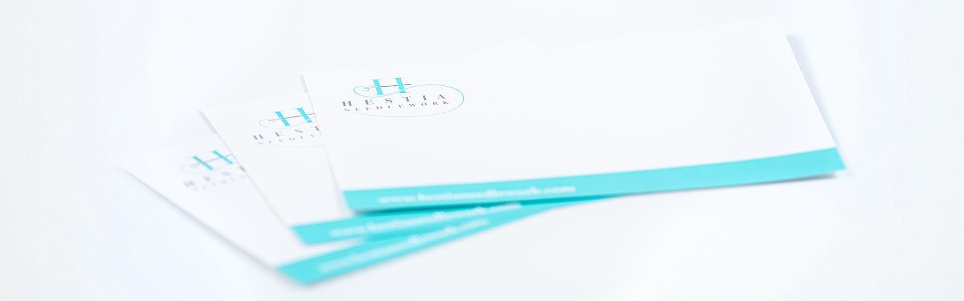three business cards for hestia needlework are stacked on top of each other 