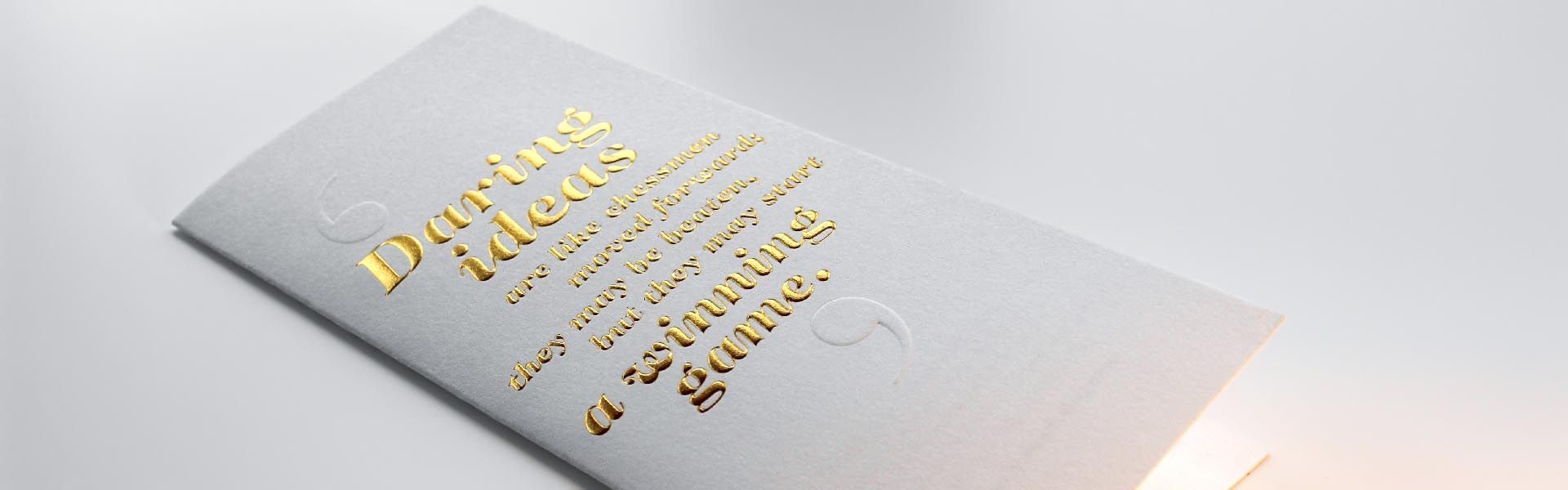 a white envelope with gold foil embossed lettering that says 