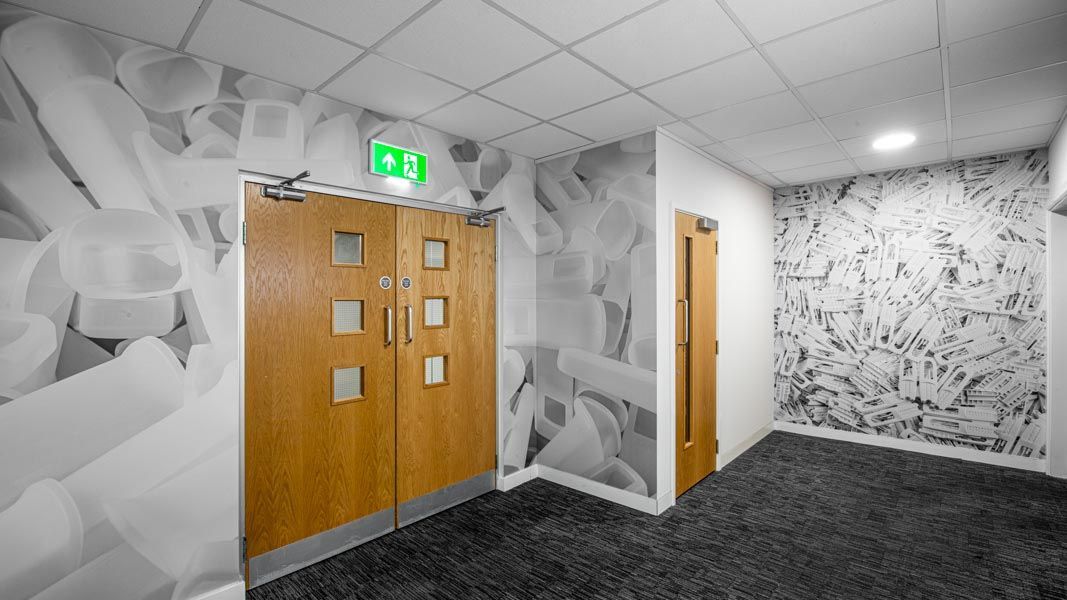 a hallway with a green exit sign on the wall with large format printed photographic wallpaper
