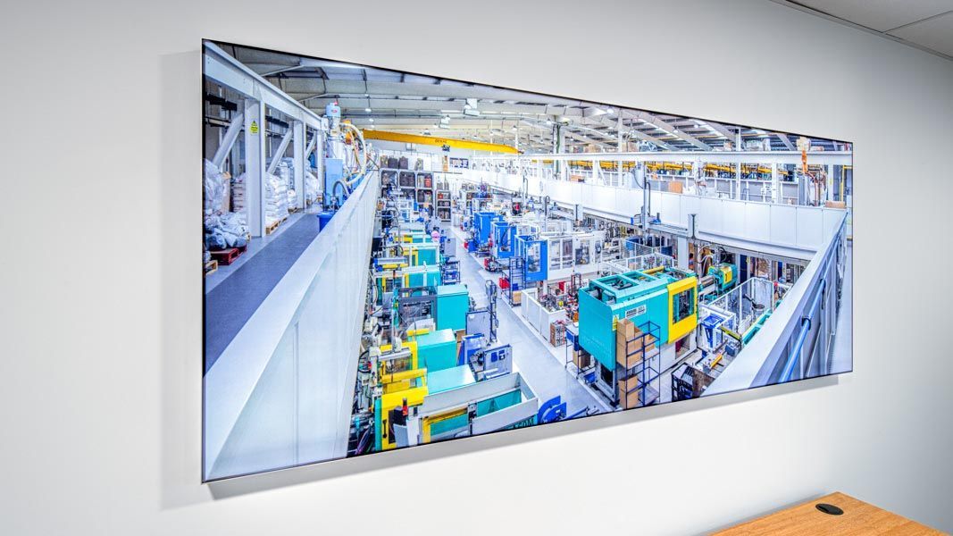 a large backlit picture of a factory with a blue machine that says ecg on it