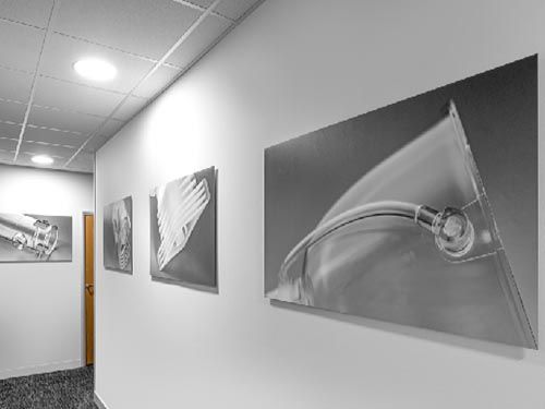a hallway with a row of photographs of injection moulded plastic components on the wall.