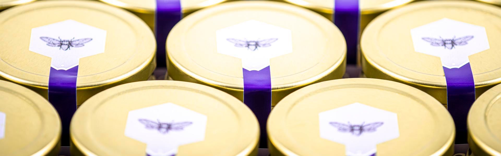 a row of gold jars with purple ribbons and bees on them