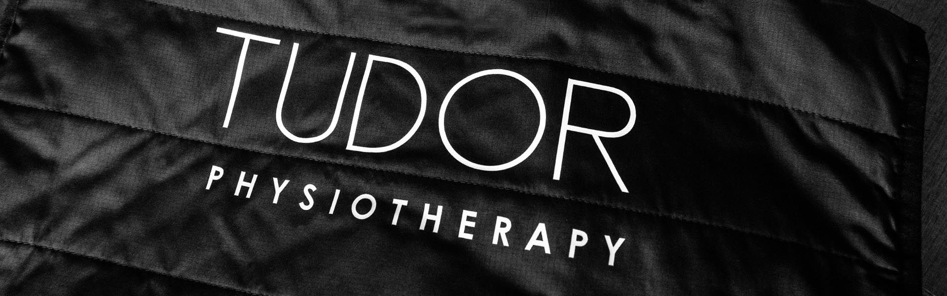 a black jacket with tudor physiotherapy printed on it