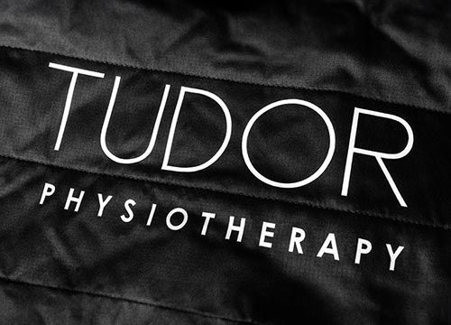 the tudor physiotherapy logo is printed on a black jacket