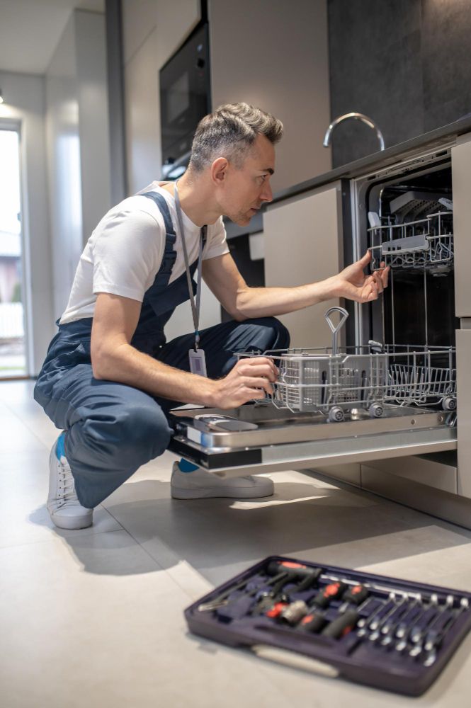 Technician inspecting open dishwasher – dishwasher repair service and dishwasher technician at work.