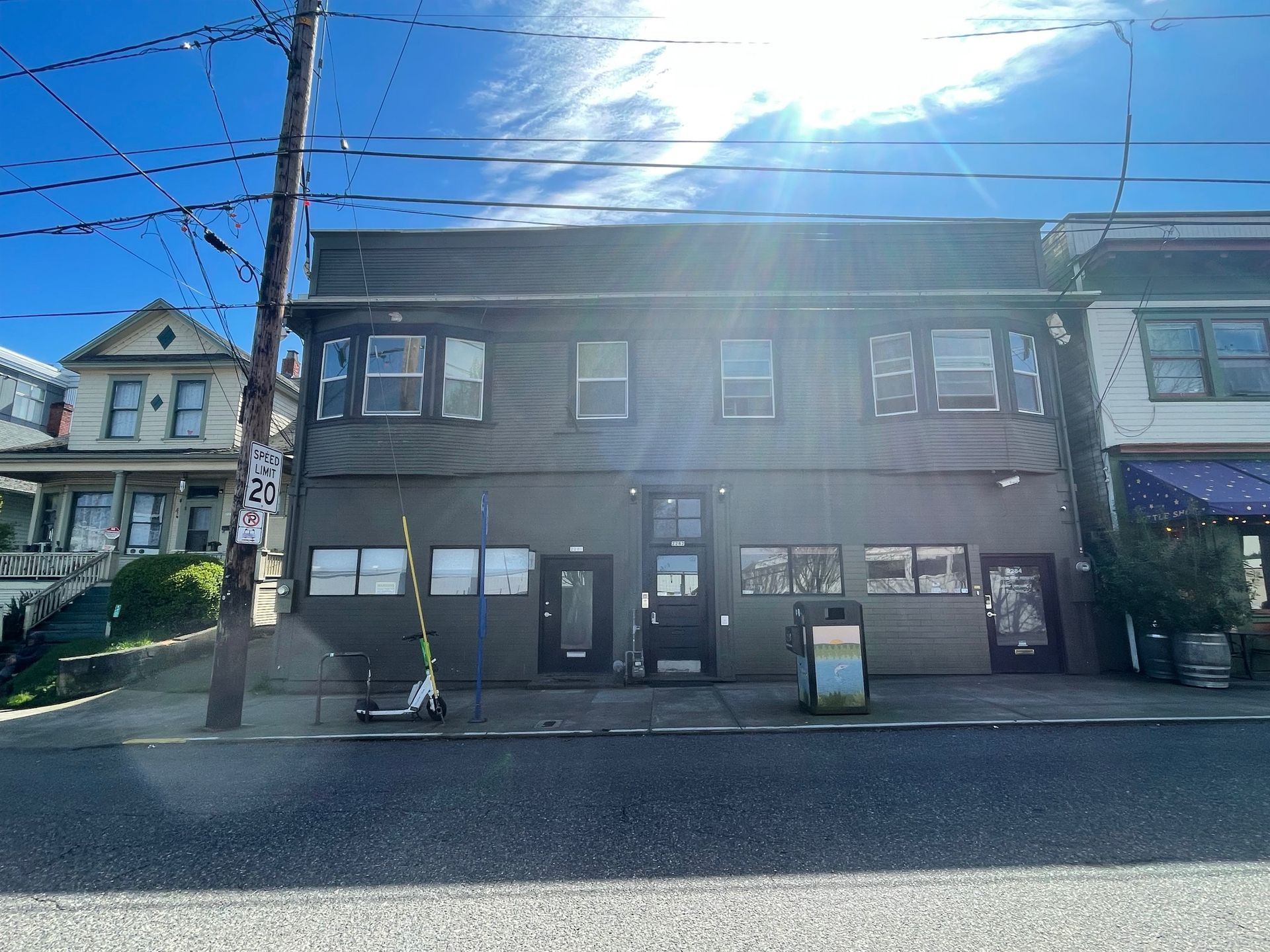 A large building with a lot of windows is sitting on the side of the road.
