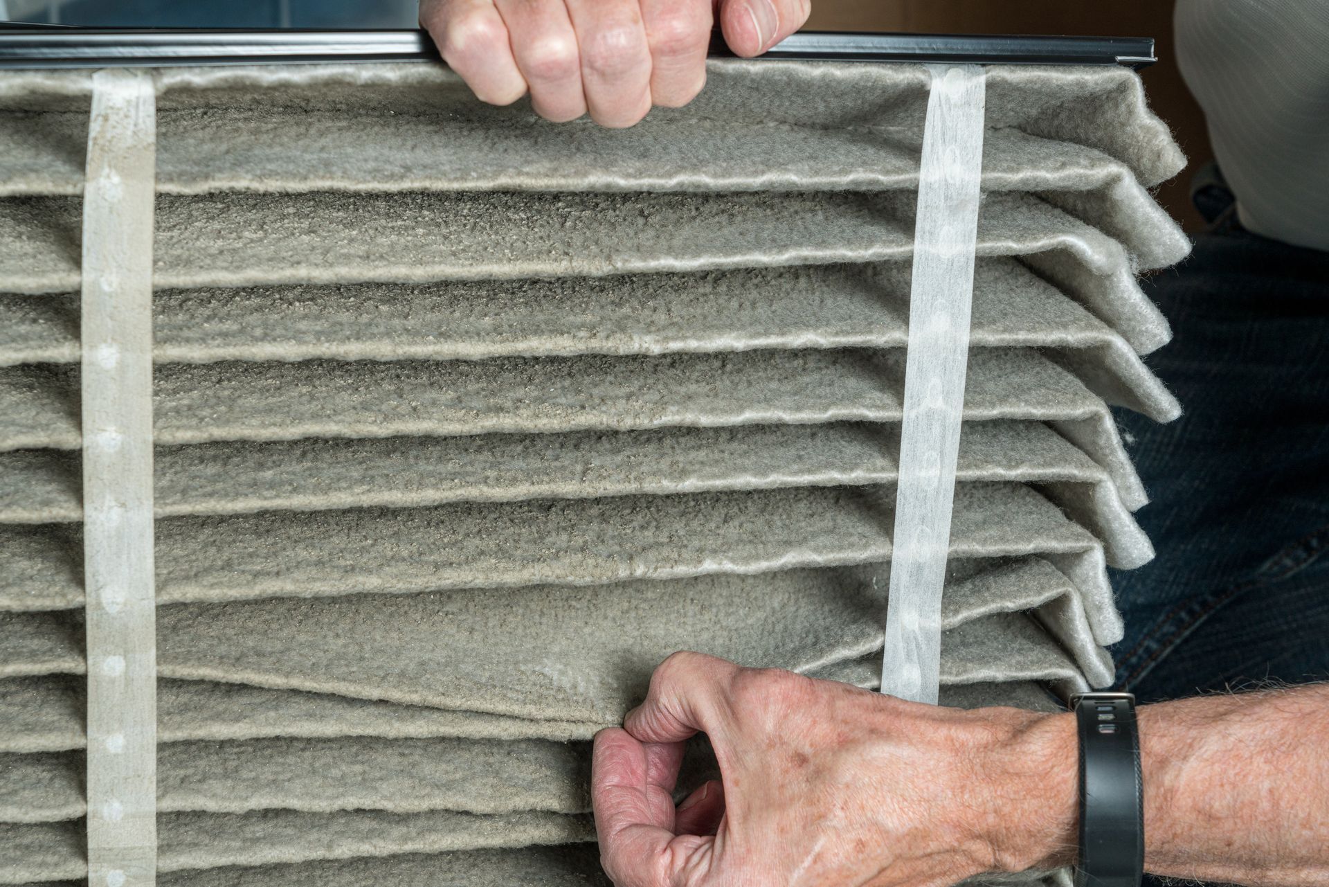 A person is holding a dirty air filter in their hands.