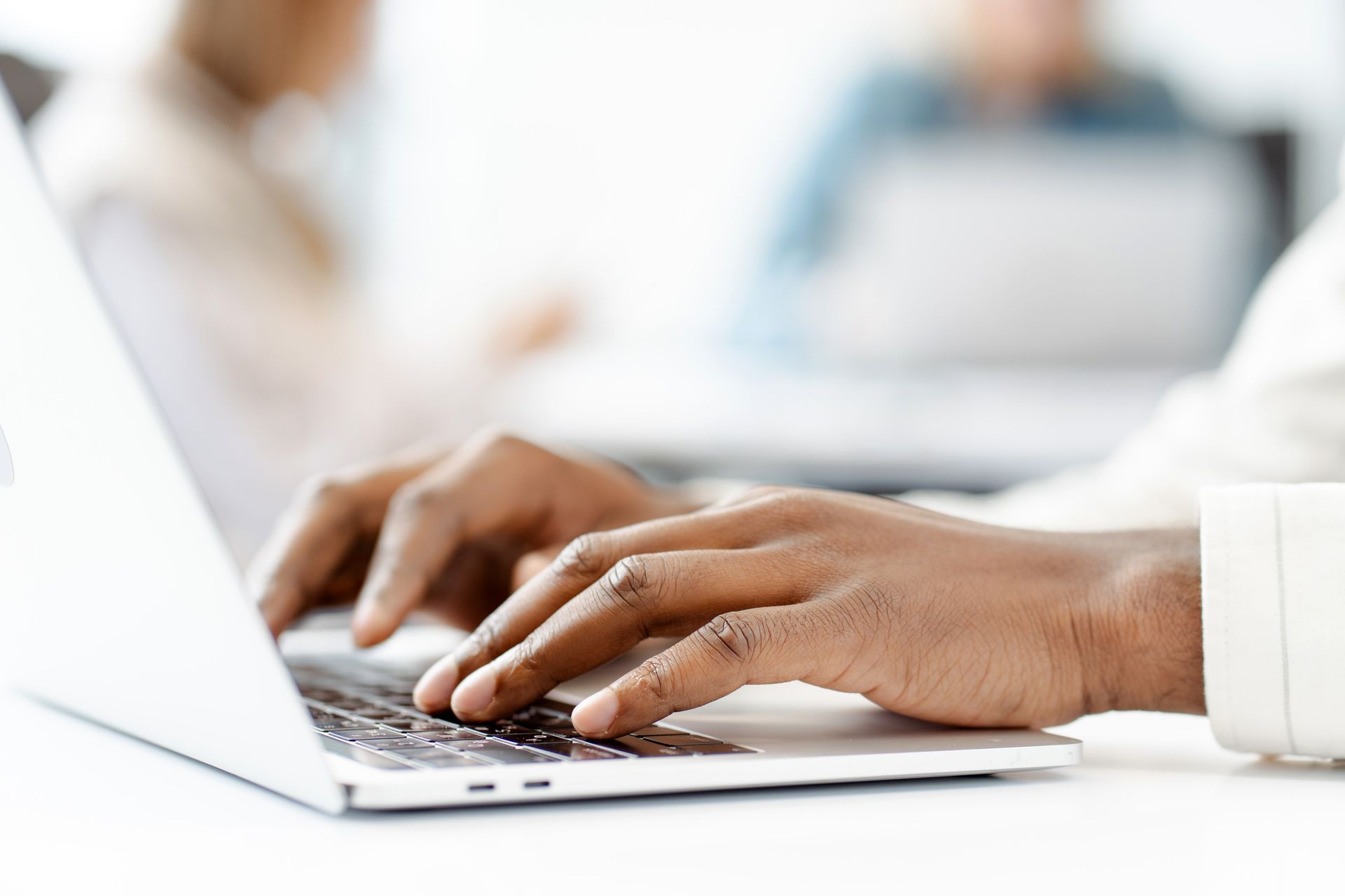 Een persoon houdt een roze pen vast in zijn hand en schrijft op een document aan een tafel.