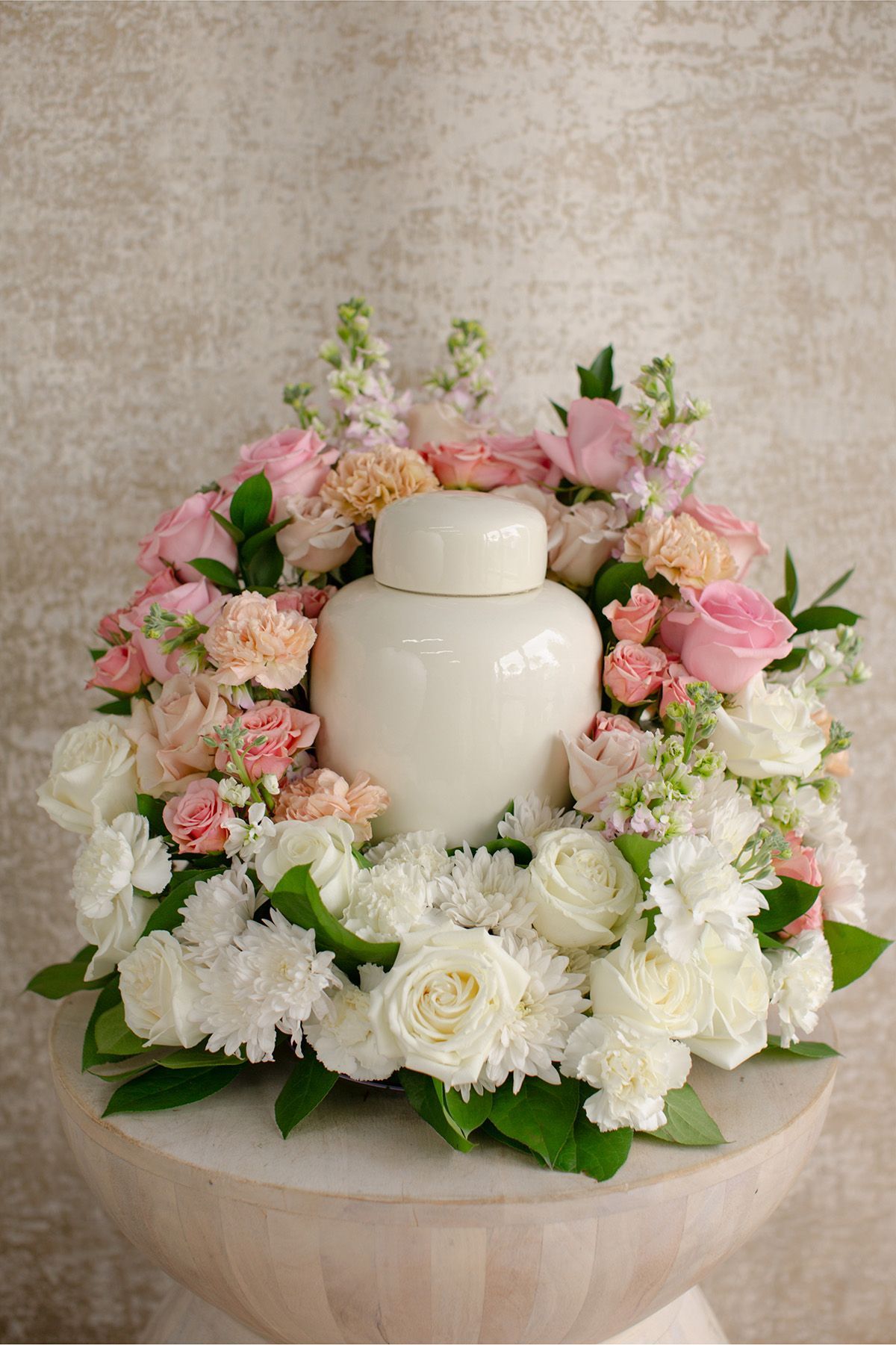 Urn with flowers, lit candles, and chimes in a softly lit memorial setting.