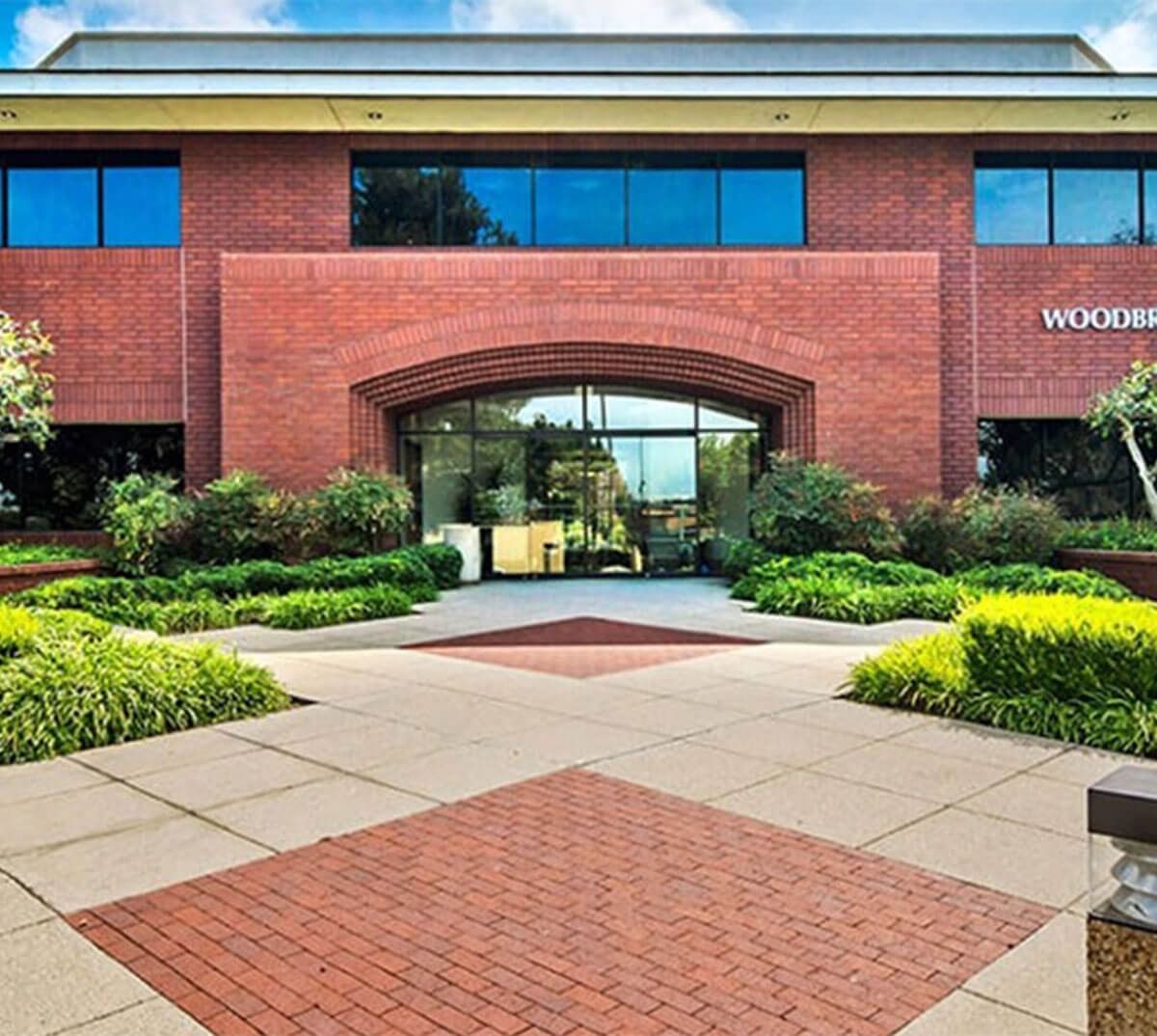 Brick office building with arched entrance and landscaped walkway.