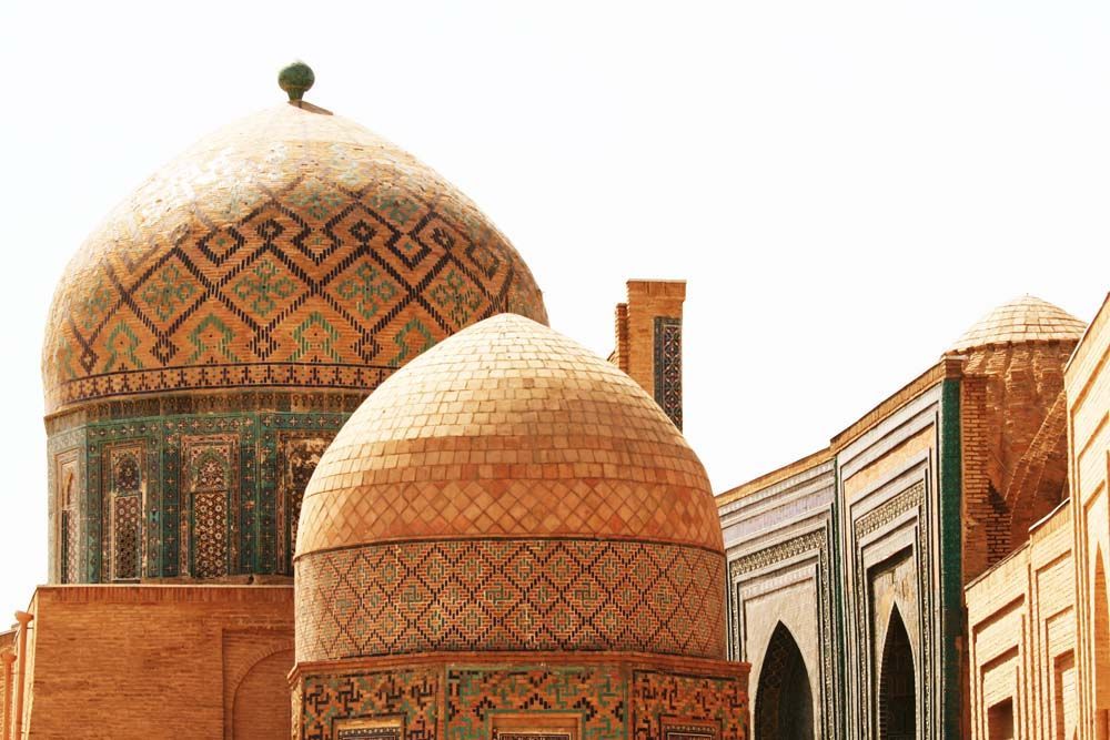 Ornate tile domes of a historic building in Uzbekistan, with intricate geometric patterns, and warm tones.