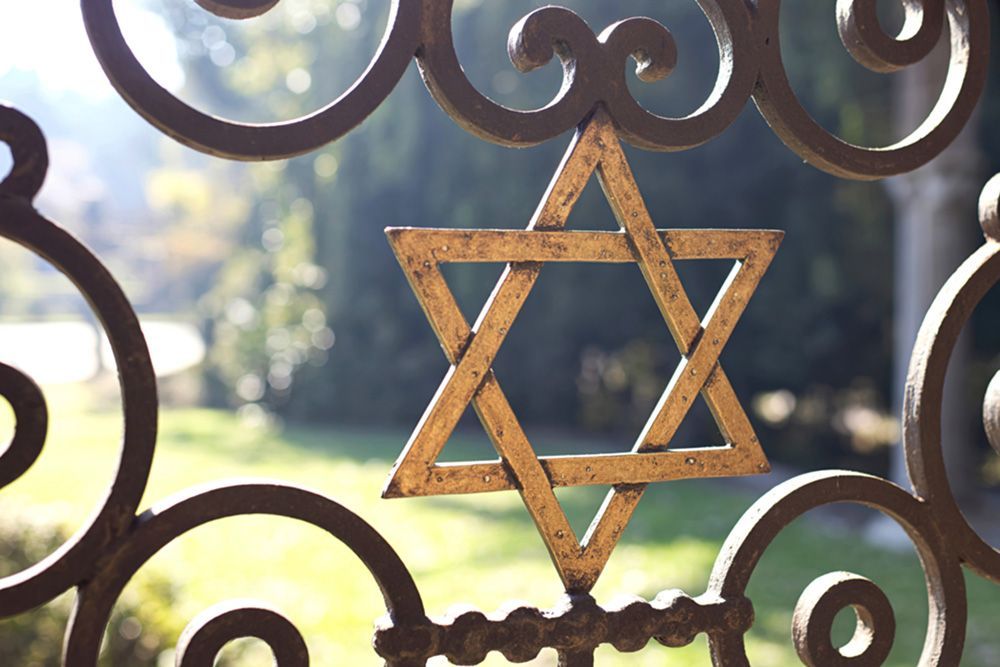 Golden Star of David on ornate ironwork, outdoor setting.