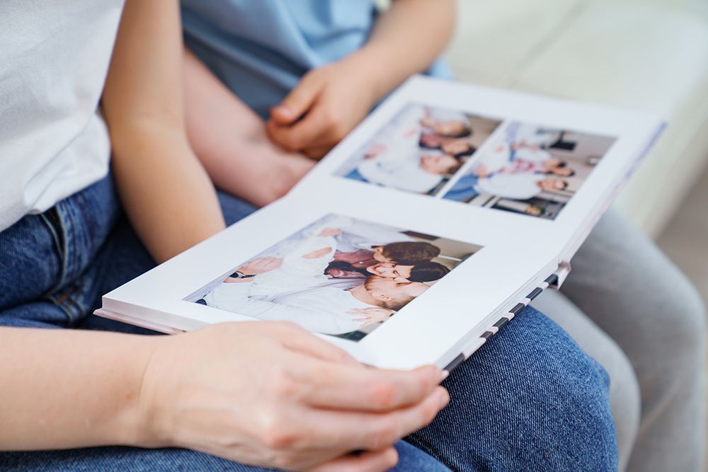 Person holding a photo album, looking at pictures with a child.