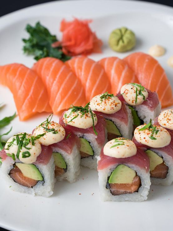 Un plato de sushi con salmón y aguacate encima.