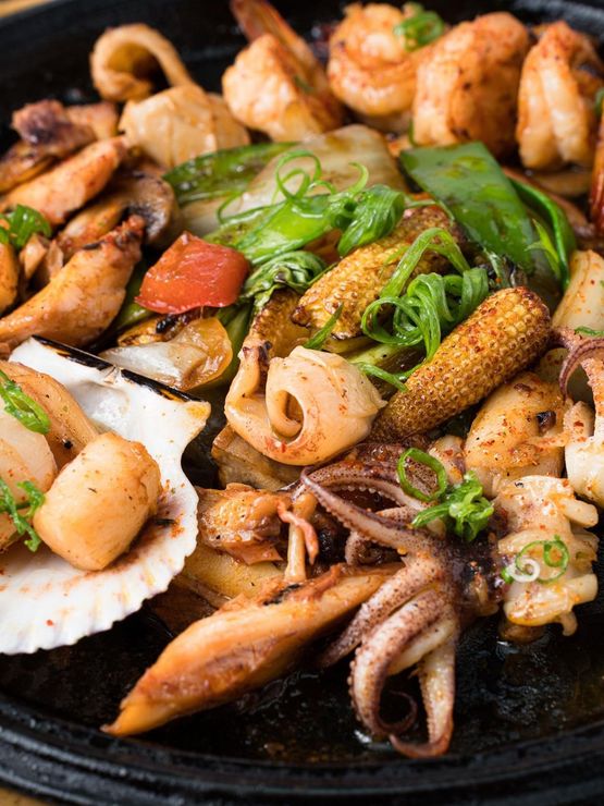Un primer plano de una sartén llena de mariscos y verduras.