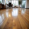 Polished hardwood floor in an empty office space with a desk, chair, and large window.