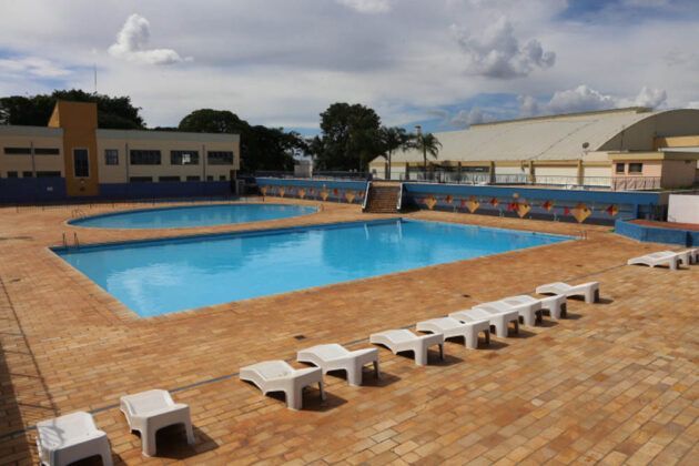 Uma fileira de cadeiras está alinhada em frente a uma piscina