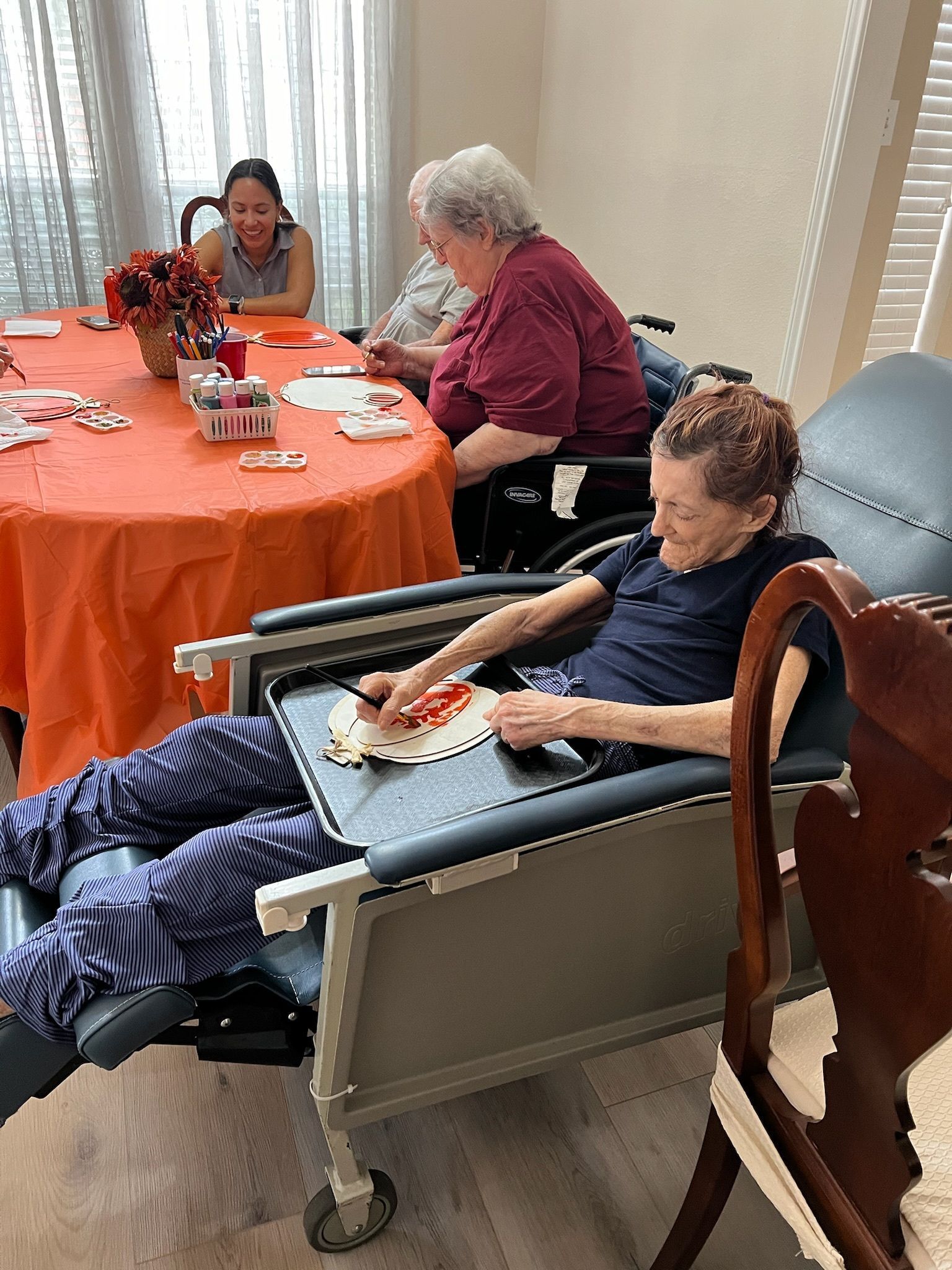 A woman in a wheelchair is sitting in front of a table with other people.