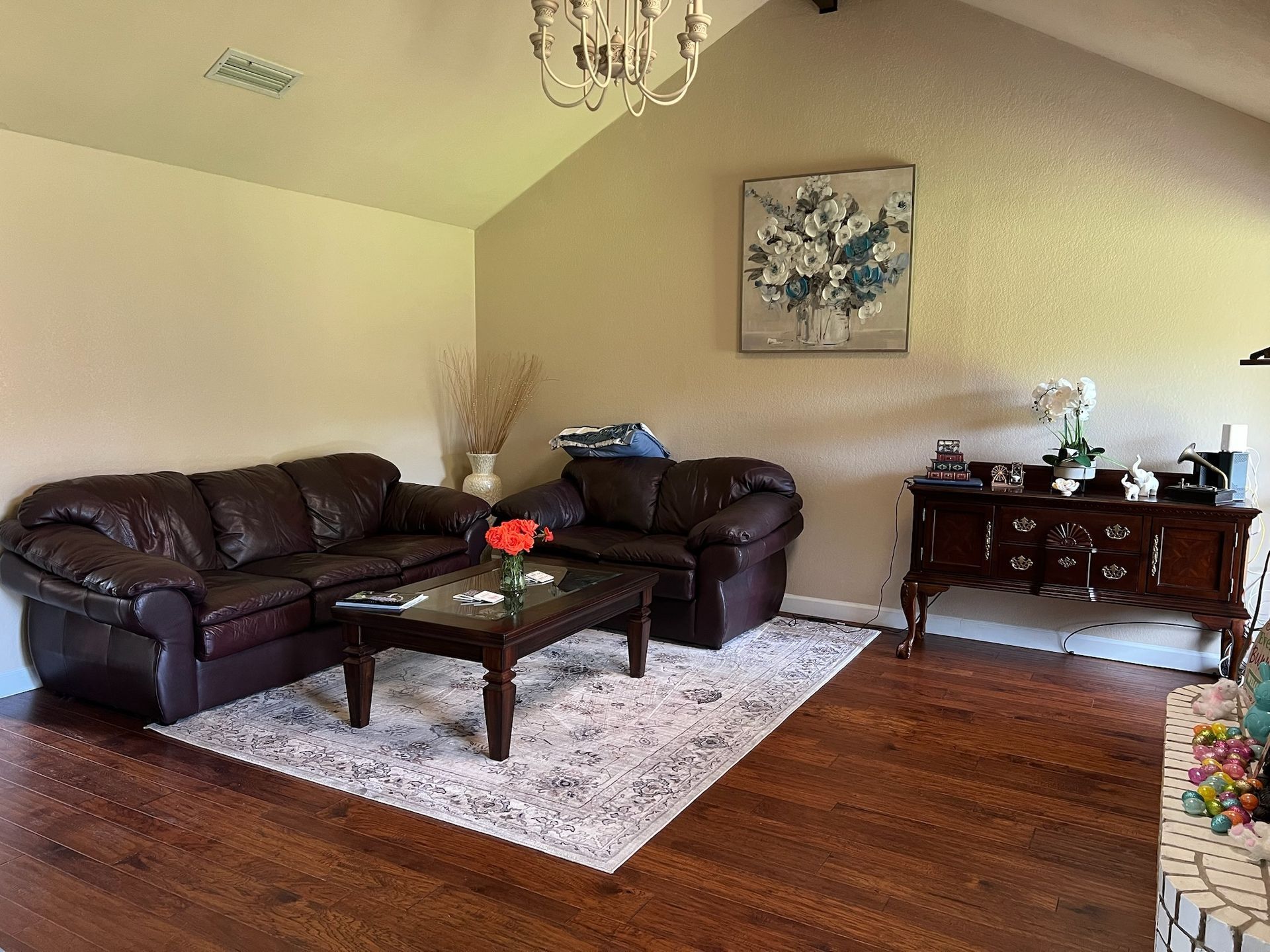 A living room with two couches , a coffee table , and a painting on the wall.
