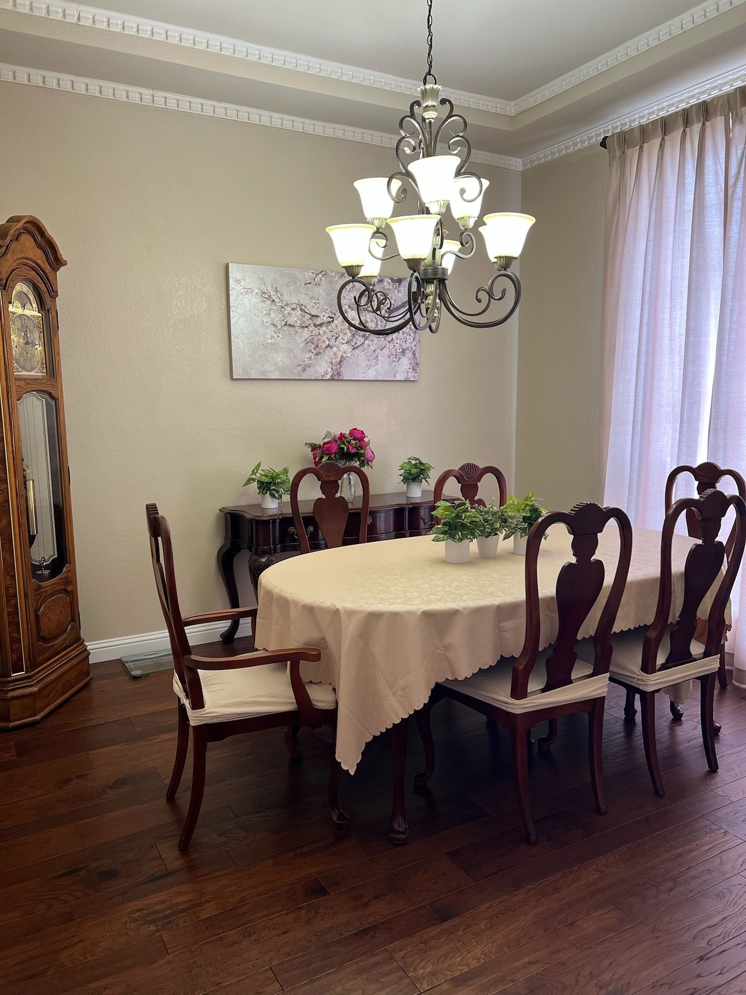 A dining room with a round table and chairs and a large clock.