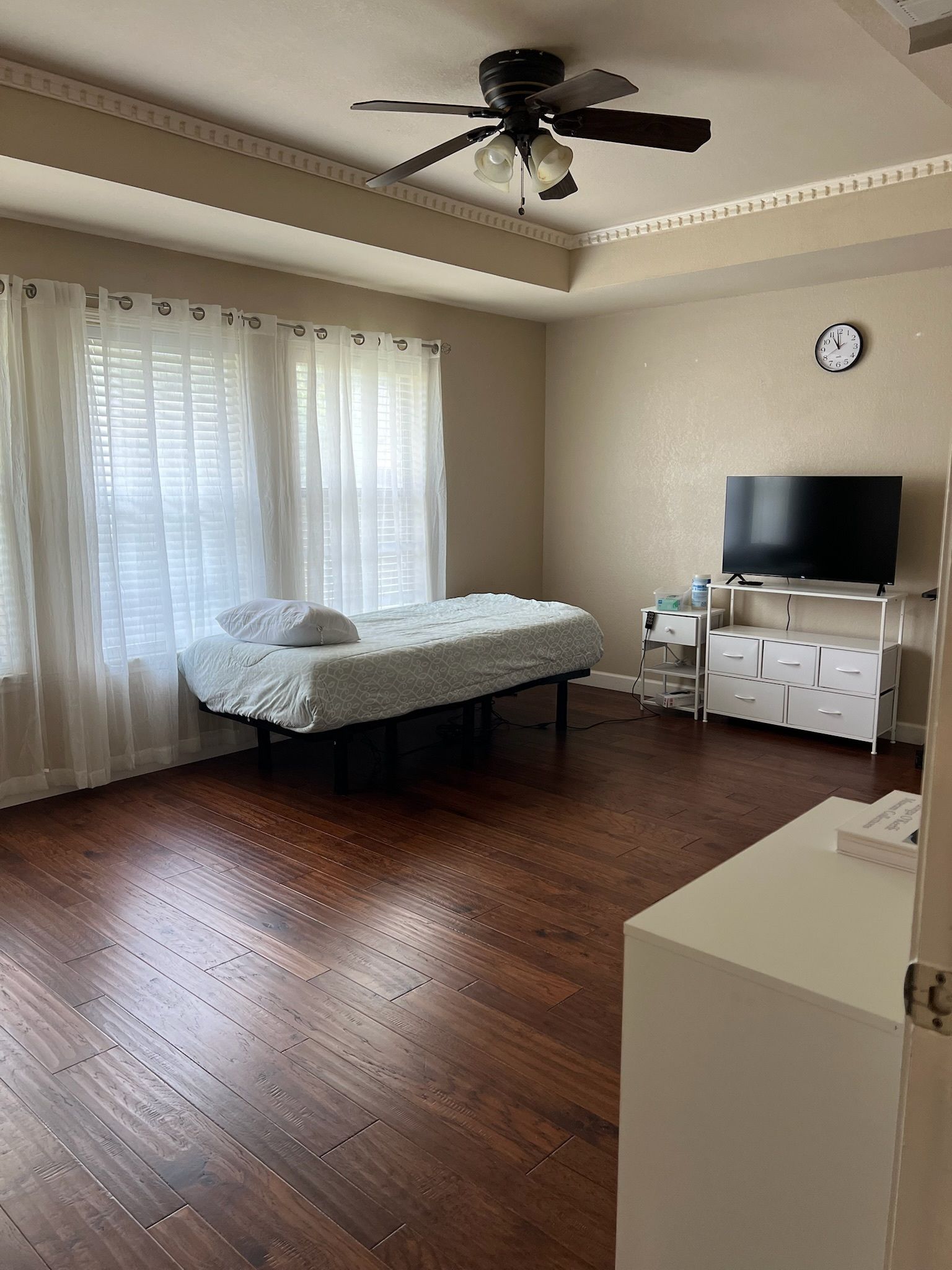 There is a bed in the middle of the room with a ceiling fan.