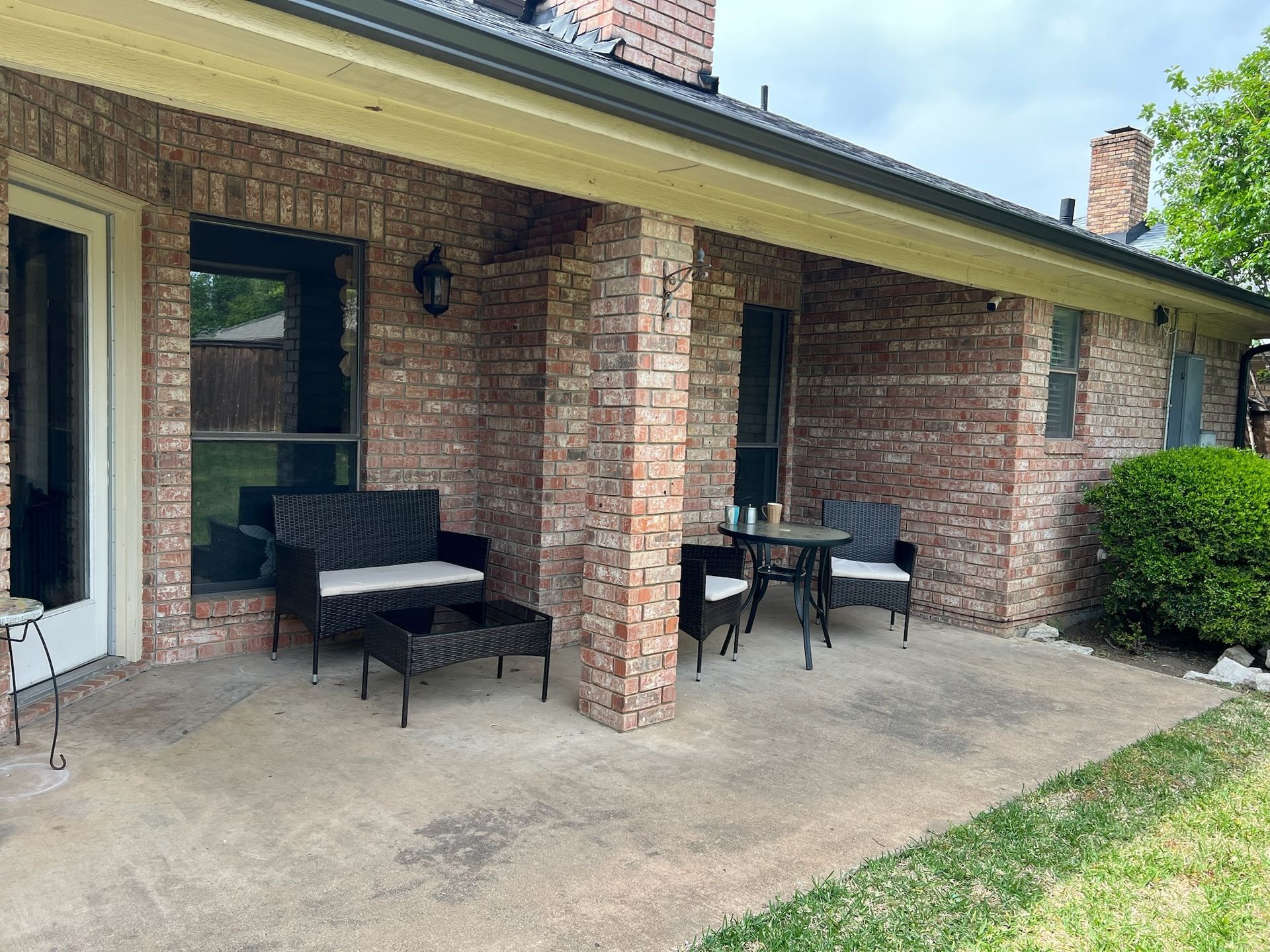A brick house with a patio area with a table and chairs.