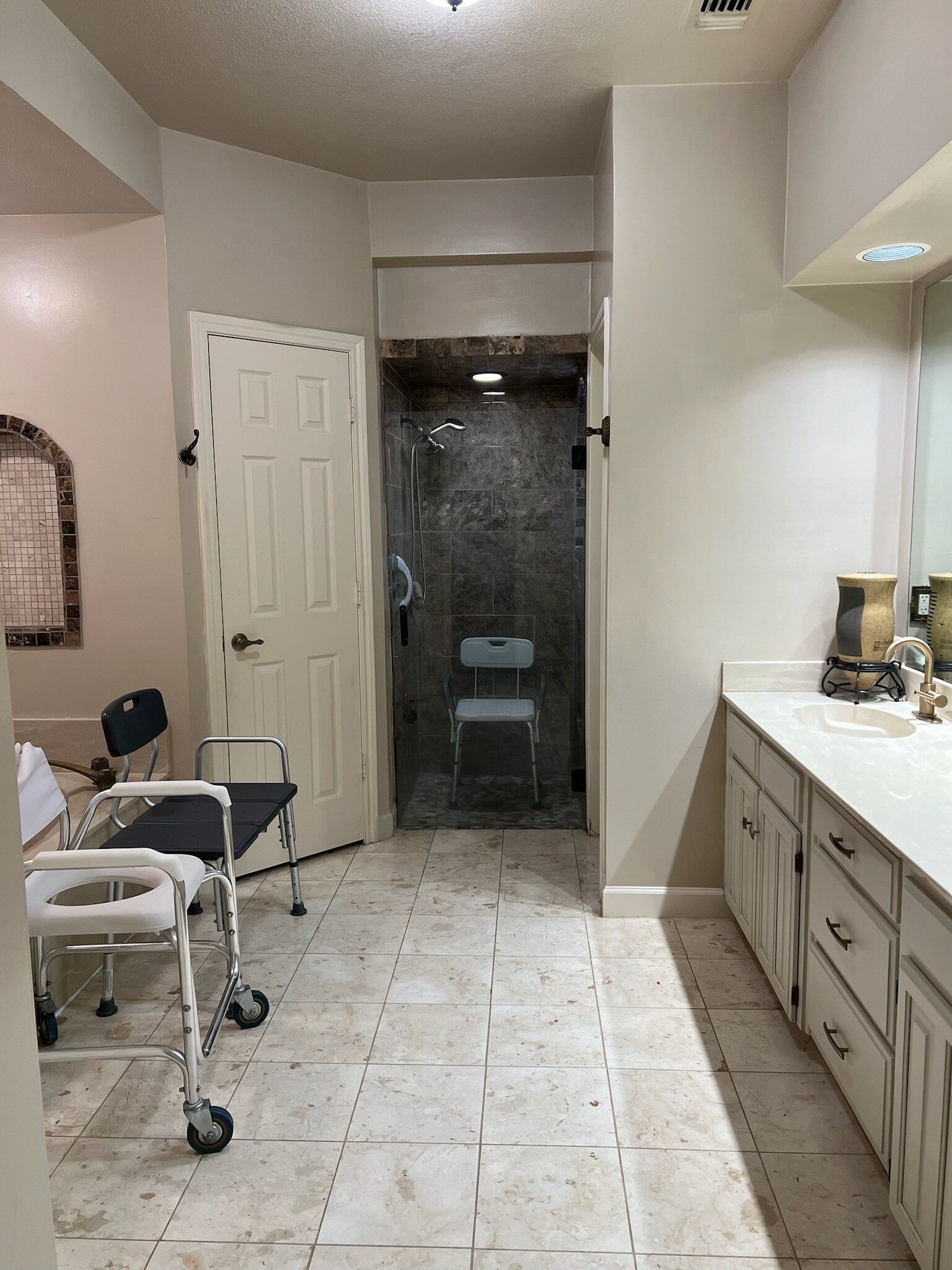 A bathroom with a walker , toilet , sink and shower.