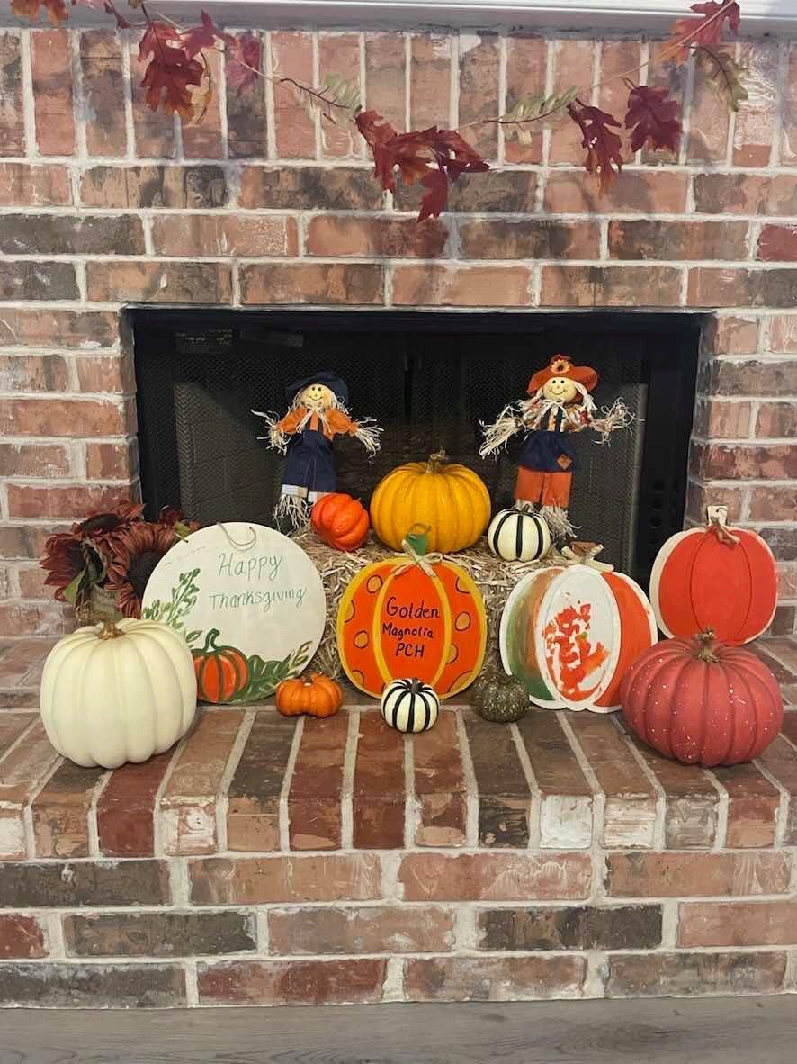 A brick fireplace decorated for fall with pumpkins and scarecrows.