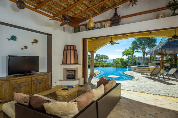 A living room with a couch , television , fireplace and a pool.