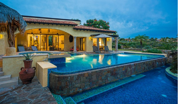 A house with a large swimming pool in front of it