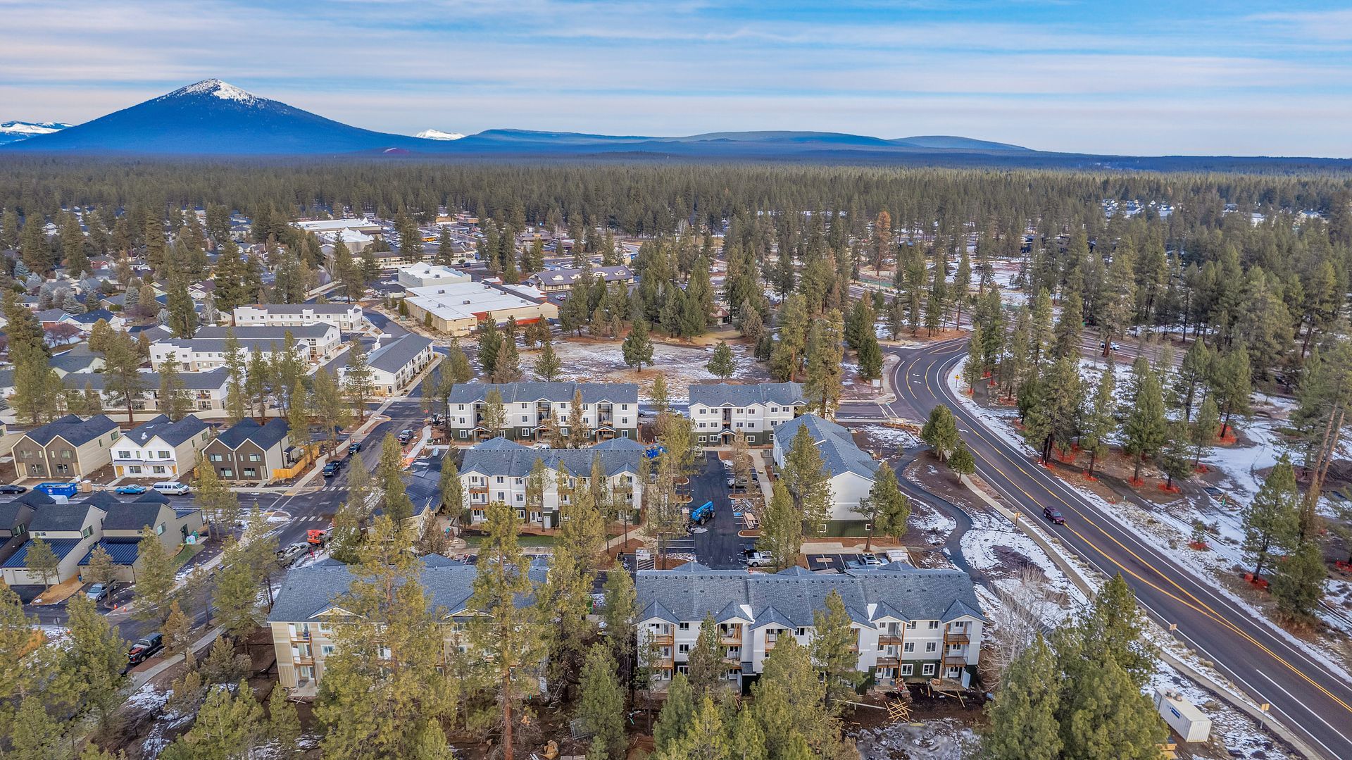 An aerial view of a small town surrounded by snow covered trees and mountains.