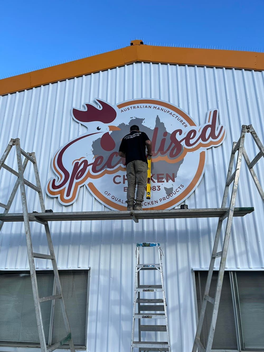 A Man Fixing a Poster With Specialised on It — Print Spot Group in South Murwillumbah, NSW