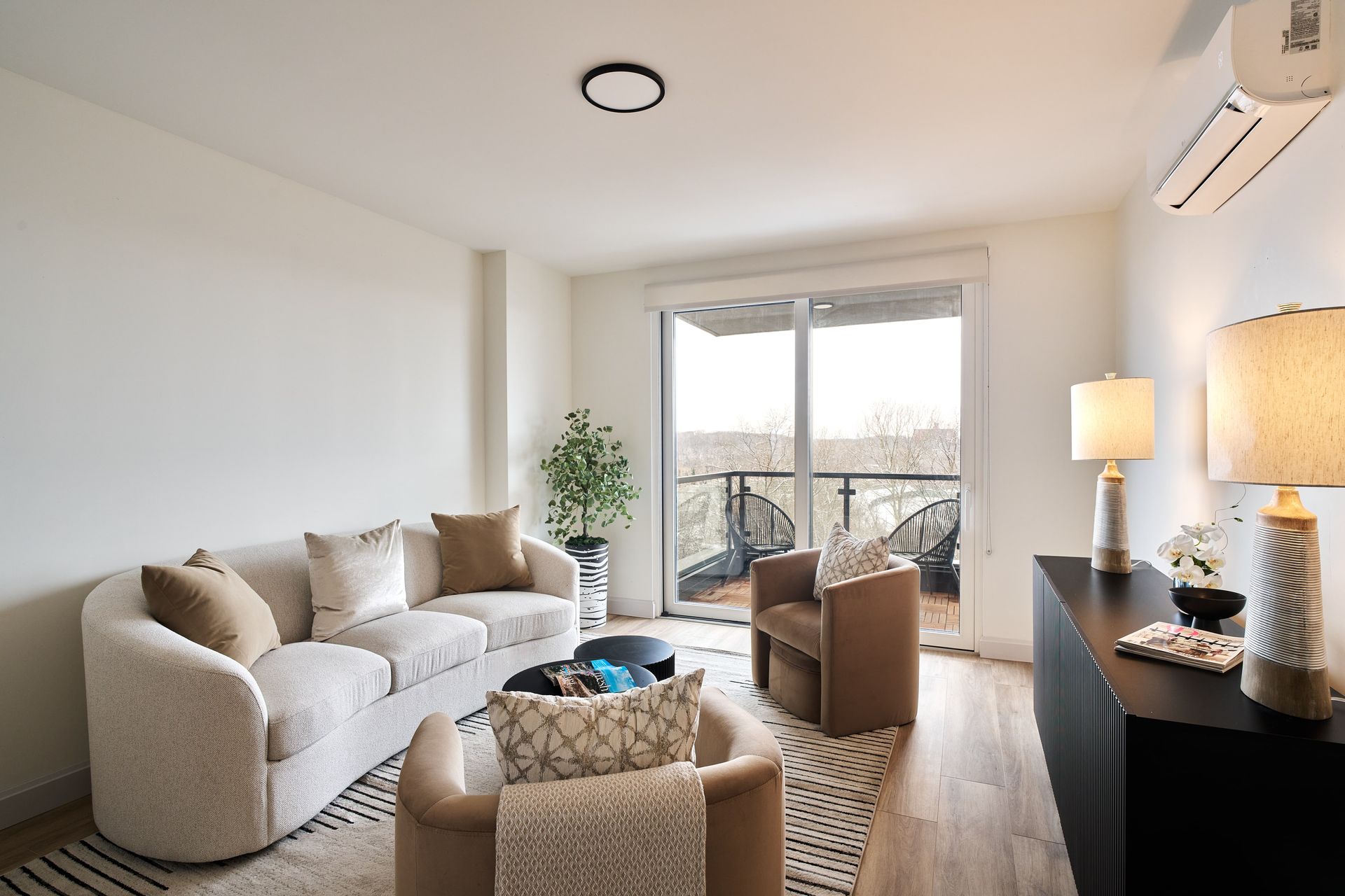 A living room with a couch and chairs and a balcony