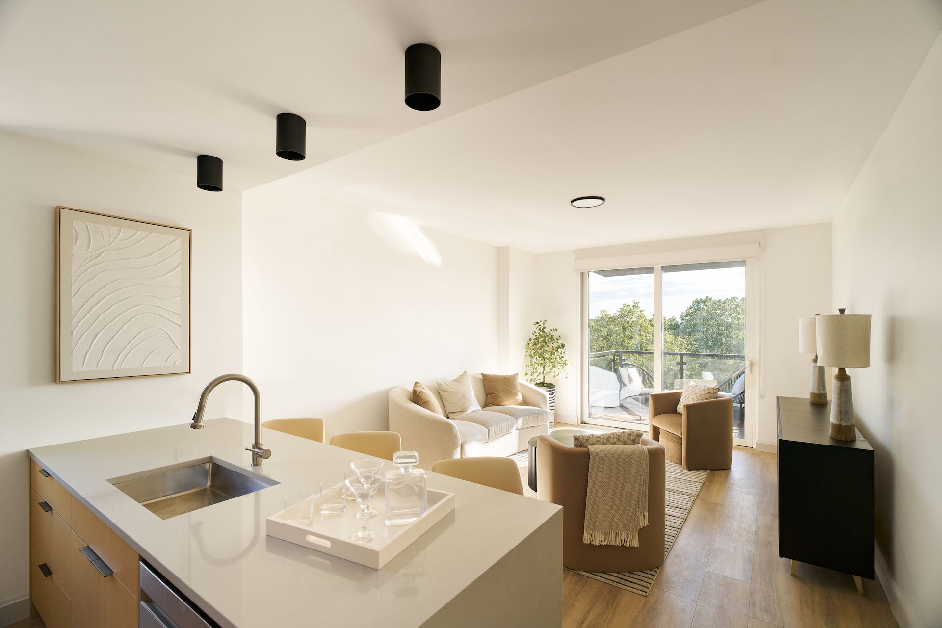 A living room with a couch , chair , table and sliding glass doors leading to a balcony.