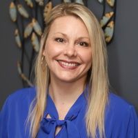 A woman in a blue shirt is smiling for the camera.