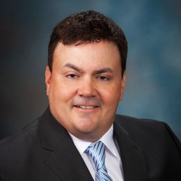 A man in a suit and tie is smiling for the camera