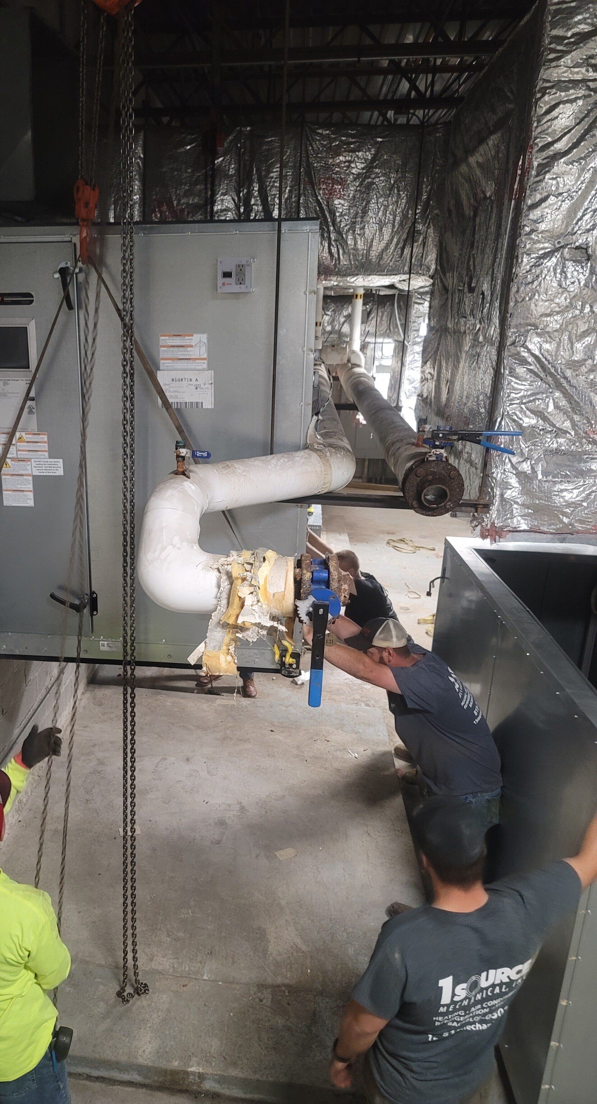 A group of men are working on a machine in a room.