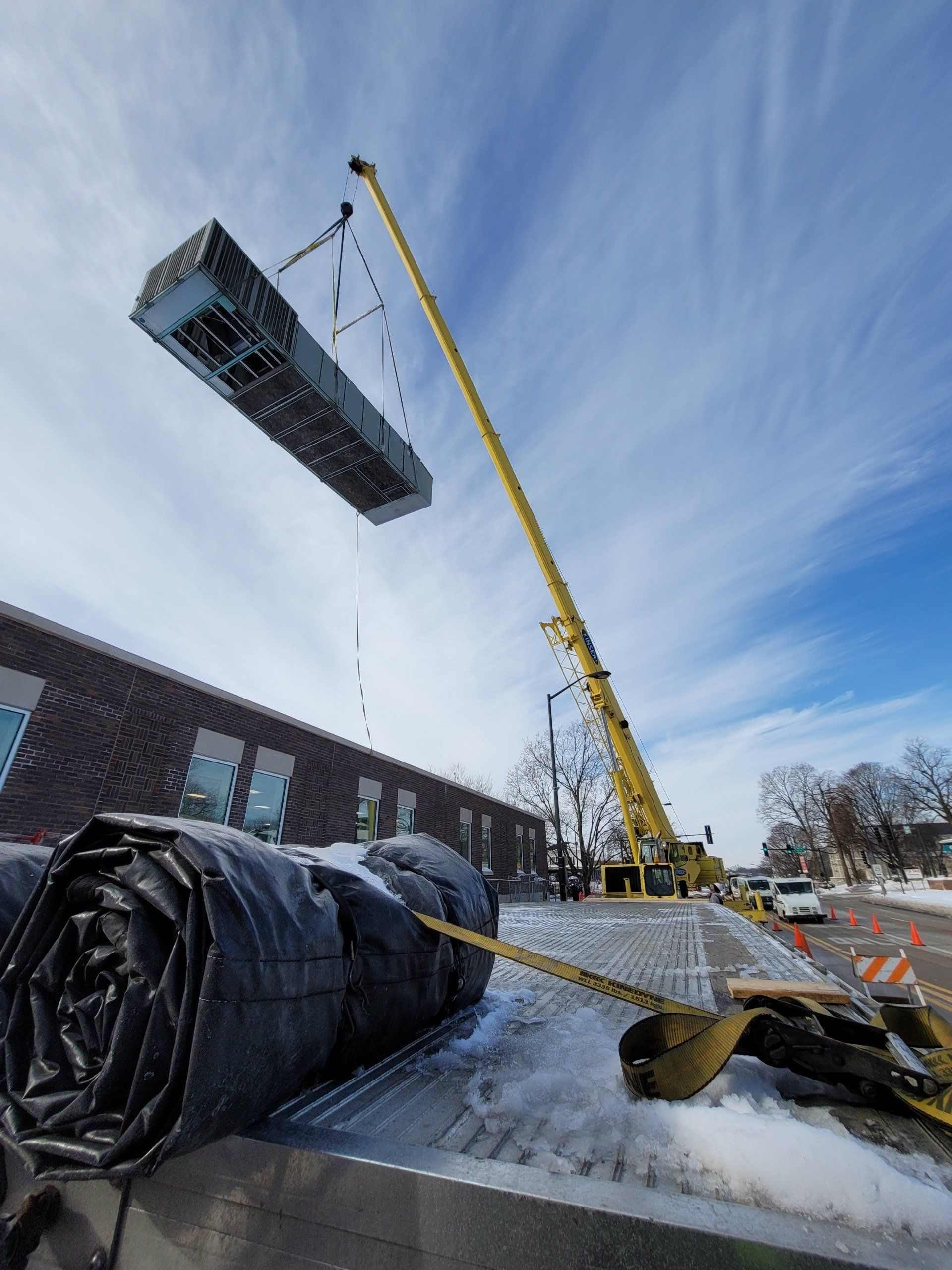 A large piece of equipment is being lifted by a crane.