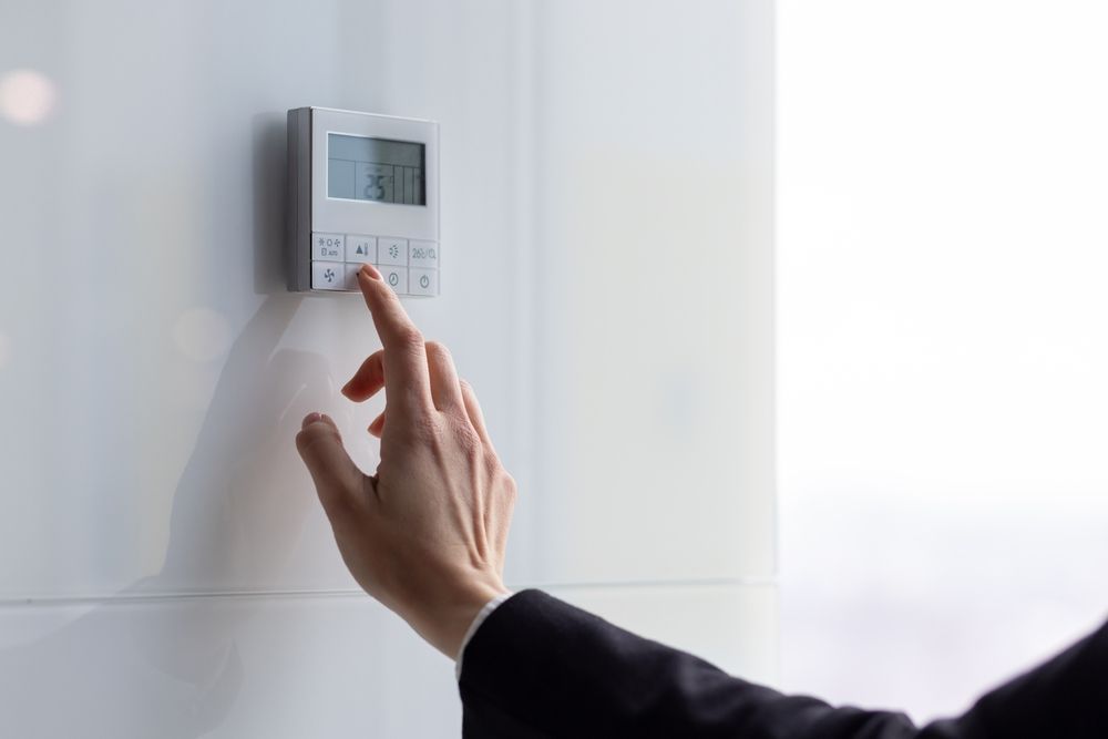 A person is pressing a button on a thermostat.