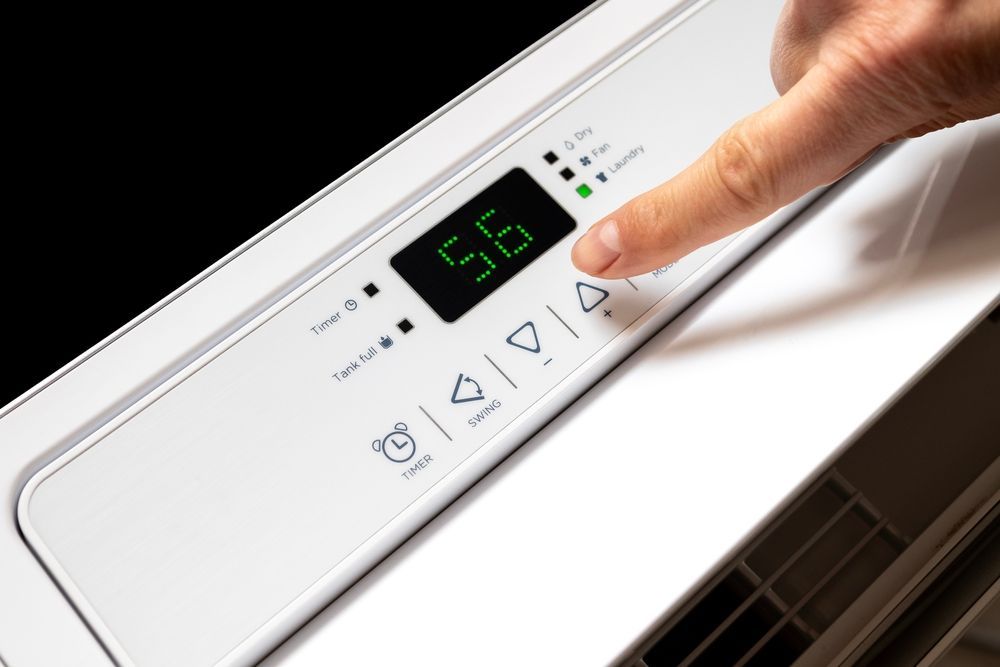 A person is pressing a button on a white air conditioner.