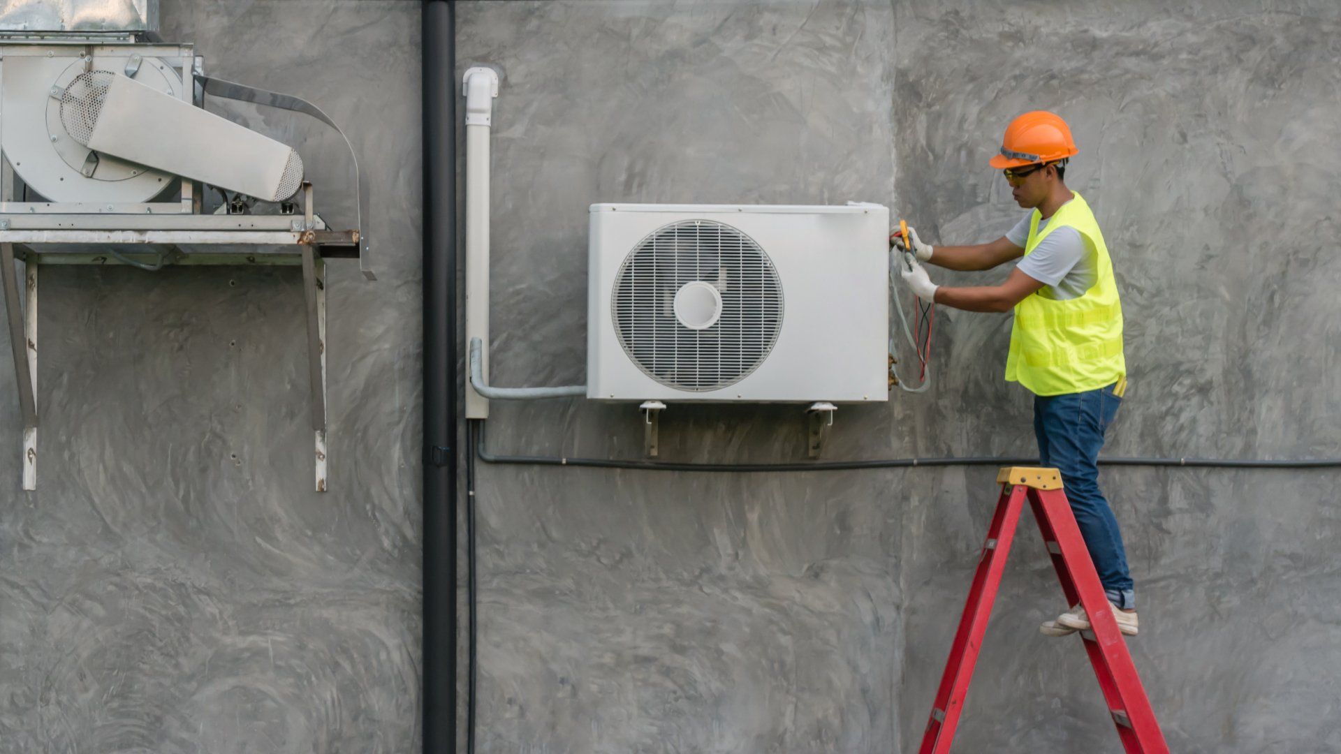 Man on ladder doing commercial hvac maintenance