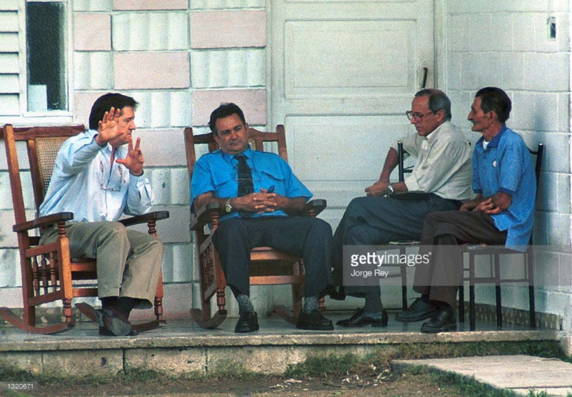 a group of men are sitting in rocking chairs on a porch .