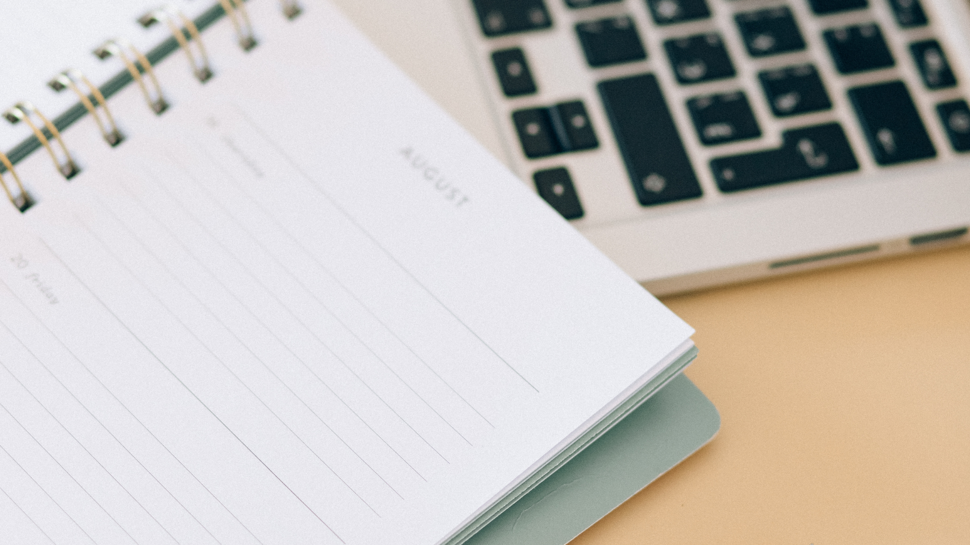 A notebook is sitting next to a laptop on a table.