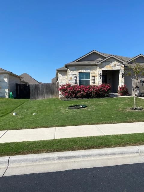 A person is raking leaves in a garden with a shovel and rake.