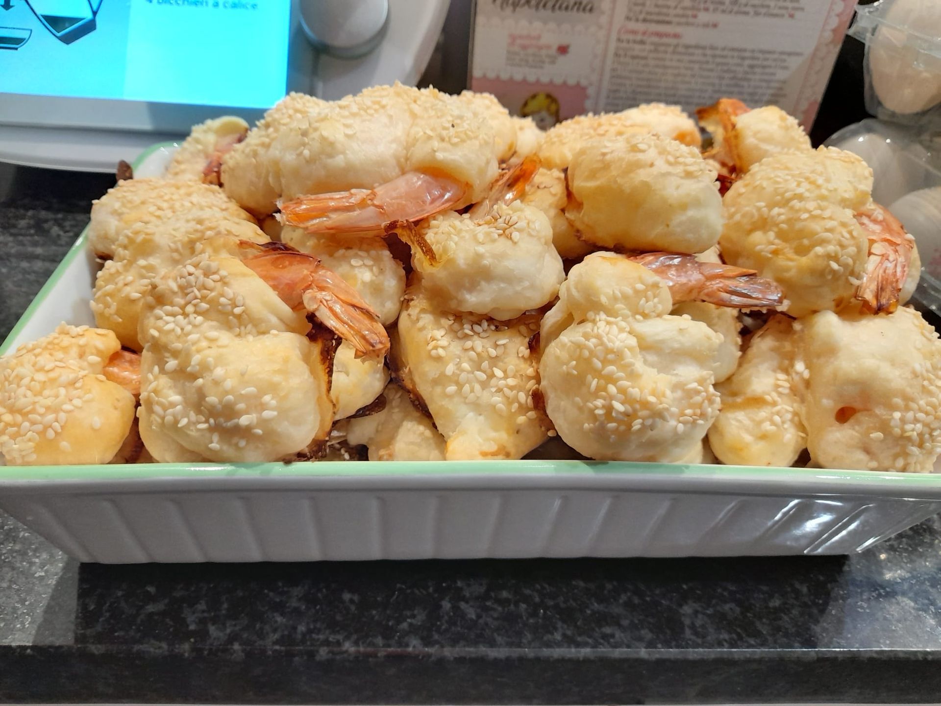 un plat blanc rempli de nourriture avec des crevettes et des graines de sésame sur une table .