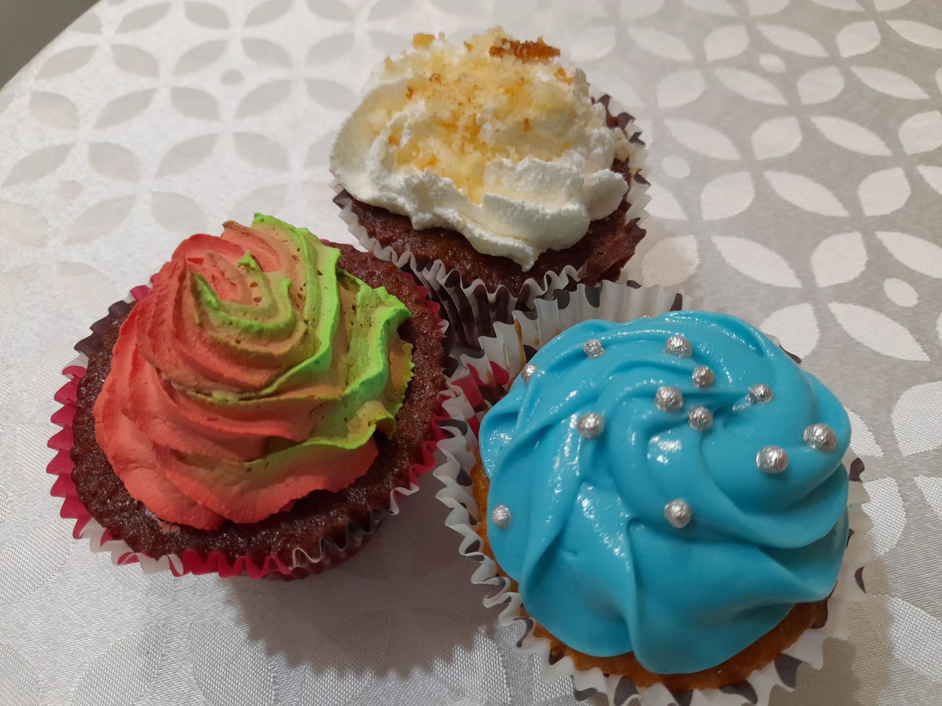 trois cupcakes avec des garnitures différentes sont posés sur une table
