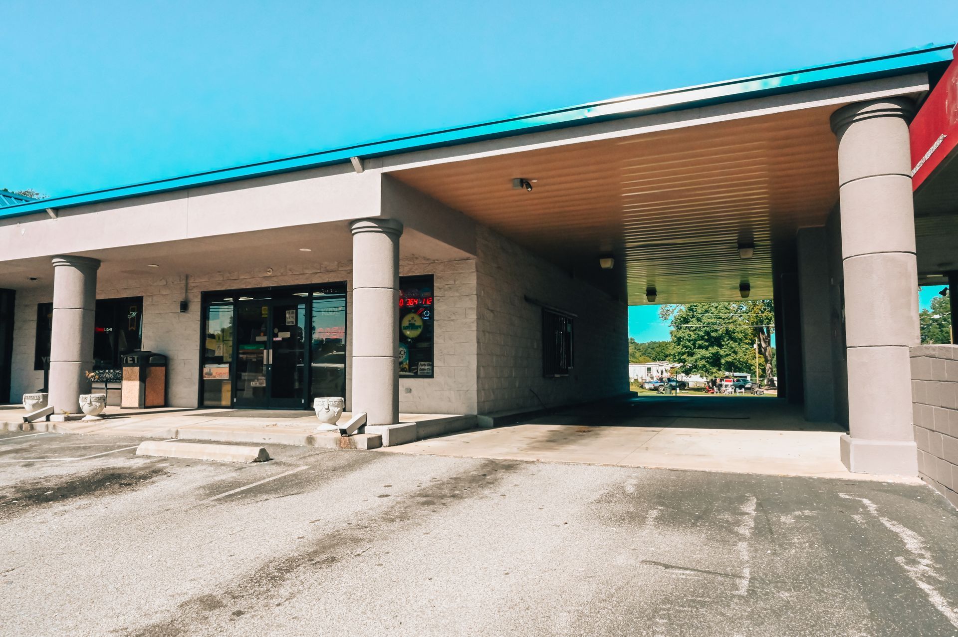 Exterior of a tan commercial building with drive-through area and blue roof against a clear sky.