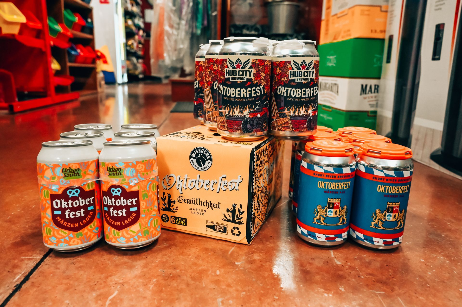 Oktoberfest beer cans displayed on a floor in a store. Some cans are in boxes, others grouped together.