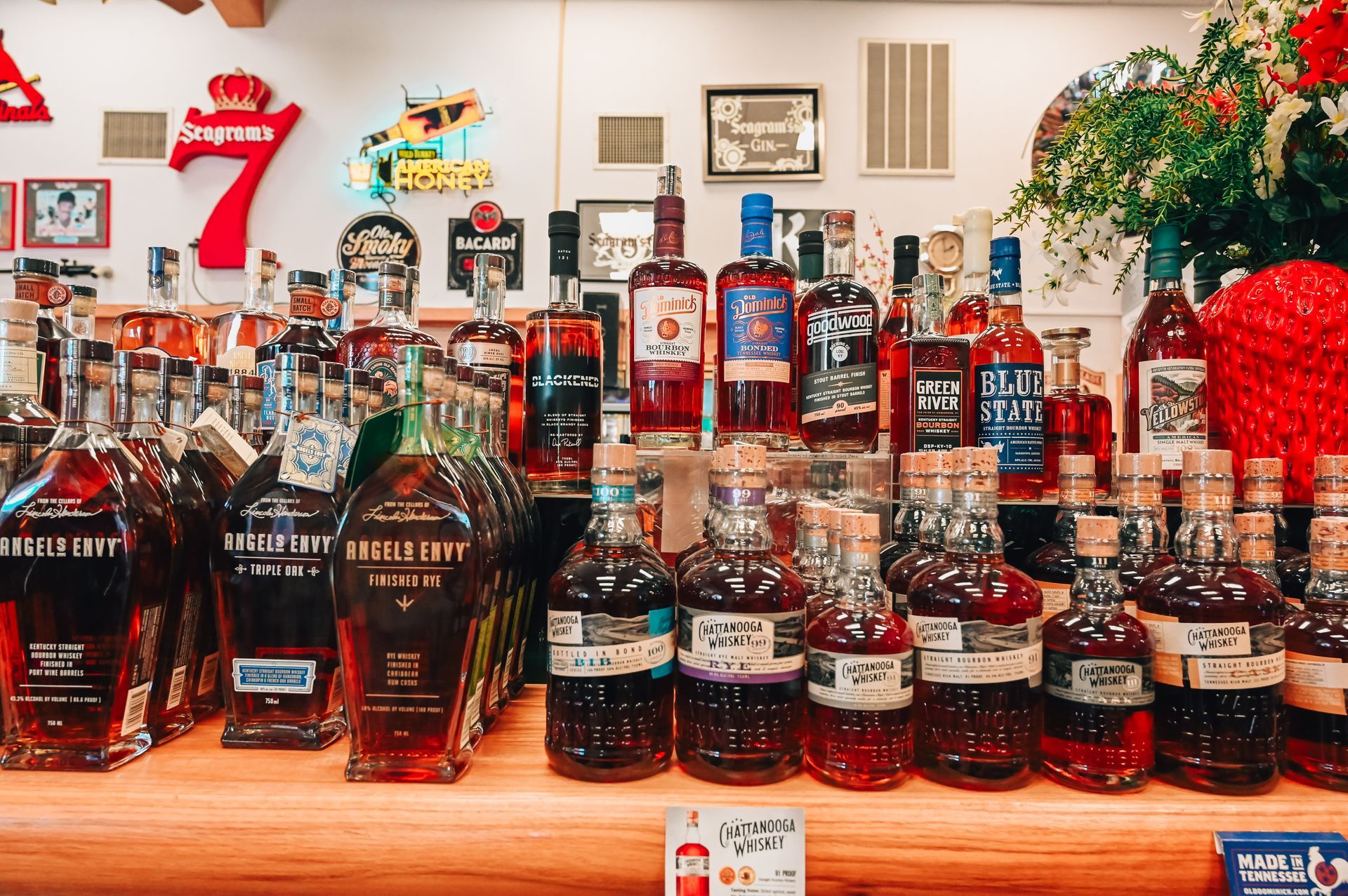 Bottles of liquor on display at a store, with colorful labels and various shapes, arranged on a wooden surface.
