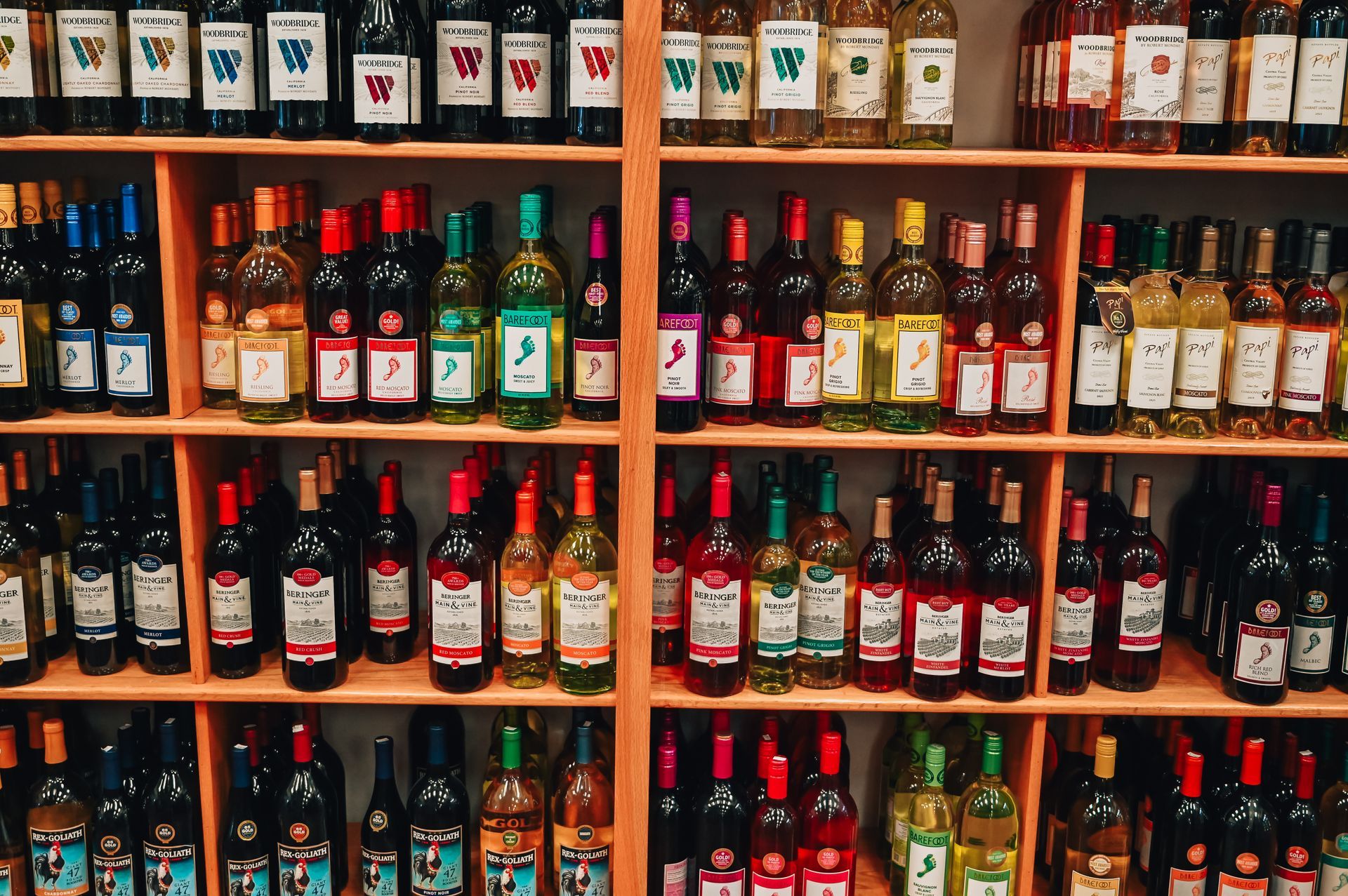 Wine bottles on shelves in a store, various colors and labels visible.